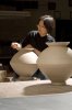 Eine Frau bearbeitet eine Keramikvase in einer Werkstatt.